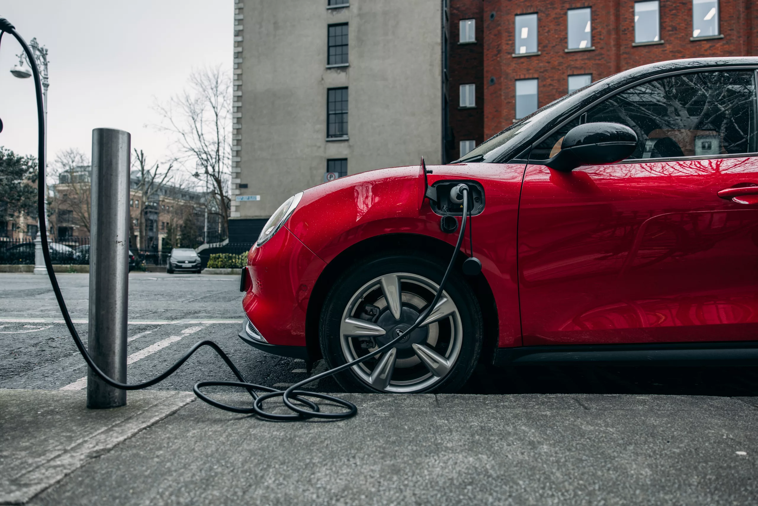 Red electric car charging at a charge point on the street